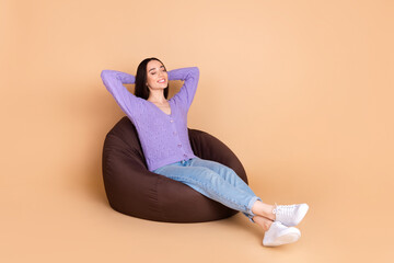 Full size photo of pretty young woman sit sleep cozy bag wear cardigan isolated on beige color background