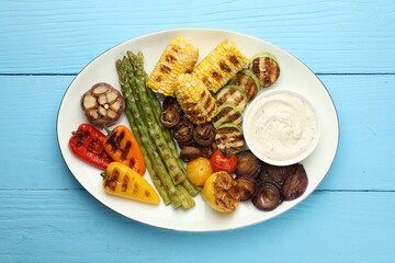 Delicious grilled vegetables with sauce on light blue wooden table, top view
