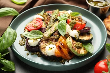 Delicious salad with grilled vegetables, pesto sauce and basil on table, closeup