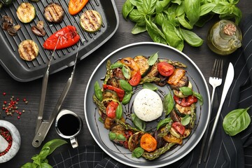 Tasty salad with grilled vegetables and mozzarella cheese served on black wooden table, flat lay