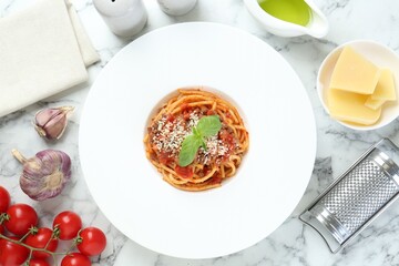 Delicious pasta bolognese with basil served on white marble table, top view