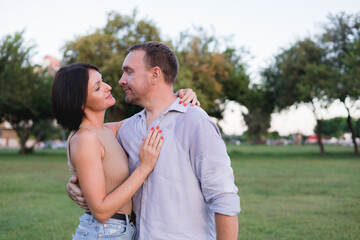 Fototapeta premium A happy smiling couple walking, hugging and kissing in park on late summer sunset