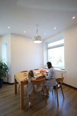 Mother and a small daughter cooking food at home in the kitchen