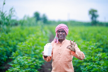 Indian village farmer holding fertilizer bottle