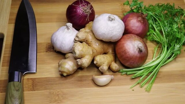 Pan shot of onion garlic ginger coriander leaf for cooking on a chopping board. Healthy cooking ingredients. Studio 4k footage. Fast food. Burger, Sandwich, pasta.

