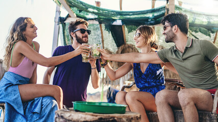 Friends toasting drinks at summer beach party outdoor celebration lifestyle