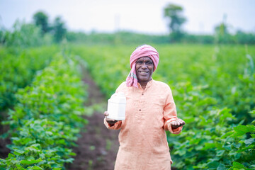 Indian village farmer holding fertilizer bottle