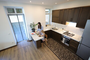 Mother and a small daughter cooking food at home in the kitchen