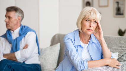 Obraz premium Sad senior woman after arguing with husband, sitting on sofa in living room
