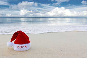 New Year 2025 background with red Santa hat on Caribbean beach.