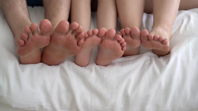 Three barefoot people, mother, father and daughter resting on the sofa, foot closeup, corns and calluses on feet, dry skin on legs, cracked heels, body care concept