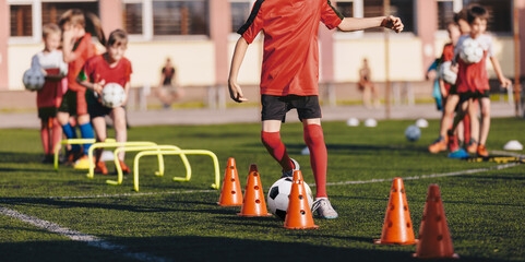 Boys attending soccer training on school field. Soccer practice for children. Young man coaching children on physical education class