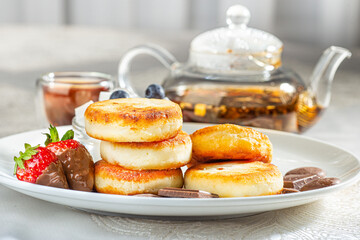 Cottage cheese pastries with strawberry, syrniki stuffed with chocolate on a white plate, selective focus
