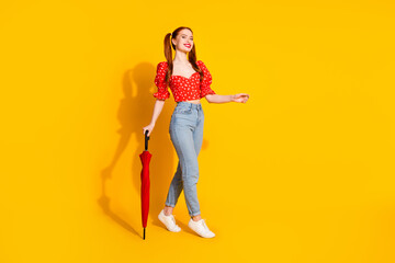 Full body length photo of young lady in red blouse and jeans holding umbrella rainy weather spring romantic season isolated on yellow color background