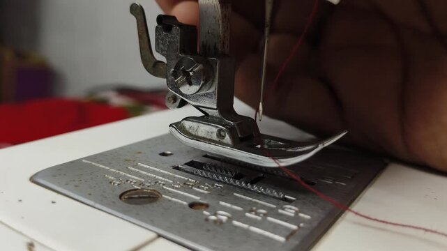 Tailor hand lowering professional clothing accessory electric sewing machine stitching hem tool and needle without fabric. Tailoring or textile industry machinery concept. Closeup macro side view.