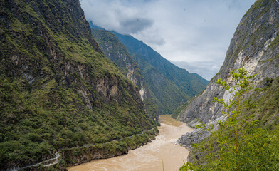 View to the steep valley of Tiger Leaping Gorge with meandering Yangtze River below in the summer of Yunnan, China.