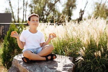 happy child meditating on a large stone in the sun, place for test