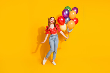Full size photo of pretty young girl hold air balloons wear trendy red outfit isolated on yellow color background
