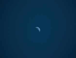 A minimalist view of the moon against a dark, clear night sky, showcasing its serene and solitary presence in the vast expanse of space