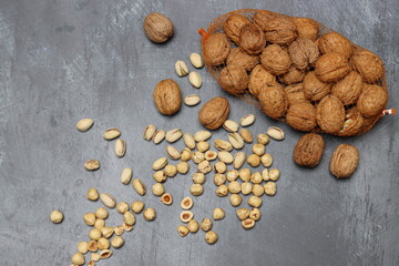 Different types of nuts on a table. Walnut, hazelnut, pistachio on grey textured background with copy space. Eating healthy concept. 
