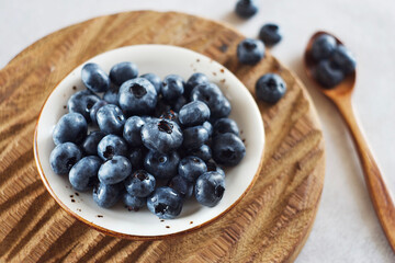 Blueberries in a plate on a wooden board. High angle view
