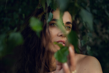 Beautiful fashion model girl enjoying nature, breathing fresh air in summer garden over Green leaves background. Harmony concept. Healthy beauty woman outdoor portrait.