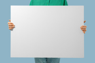 Unrecognizable person holding white canvas with empty place for text in hands