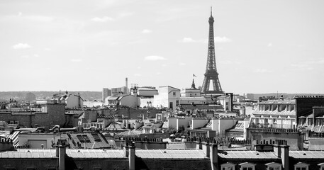 Panoramic view above the roofs of Paris, France with iconic Eiffel tower blurred in the background....