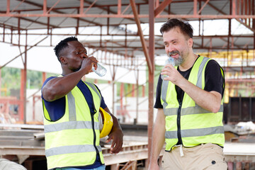 Engineer stands drinking water and working at construction site.