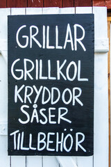 Oregrund, Sweden A sign in Swedish on the side of a red barn advertises Grills, coal, spices, sauces and extras.