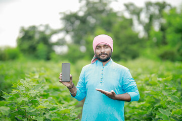 happy young Indian farmer using smart phone
