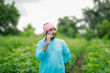 happy young Indian farmer using smart phone