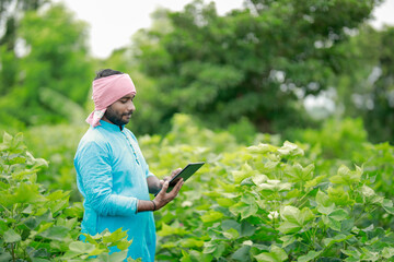 happy young Indian farmer using smart phone