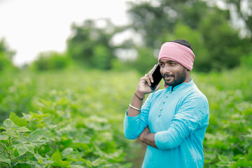 happy young Indian farmer using smart phone