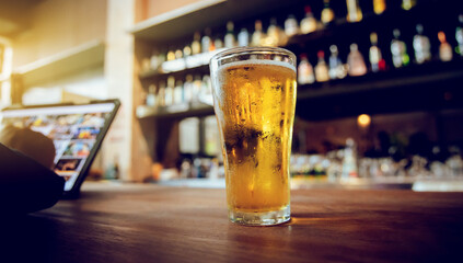 A man pours frothy beer into a glass at a lively pub. Friends gather around the bar, enjoying drinks and celebrating, with a warm, golden glow highlighting the joyful, friendly atmosphere.