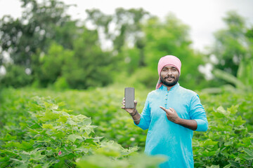 happy young Indian farmer using smart phone