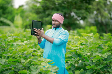 happy young Indian farmer using smart phone