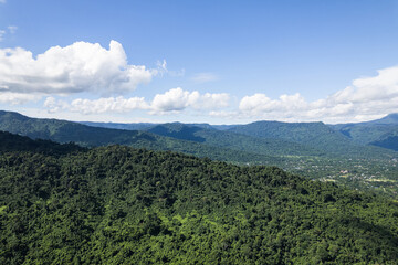 Fototapeta premium Beautiful aerial view of lush green forest and mountains under cloudy sky.
