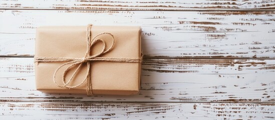 A small decorative gift box sits on a white wooden table background with copyspace