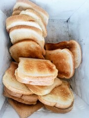 Close up of lots of of toasted crispy bread in white panier. Many toast ready to be served.