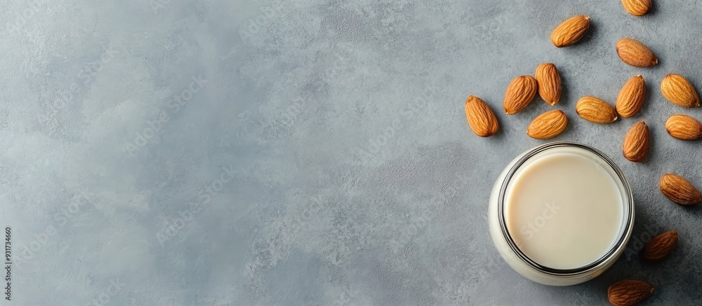 Poster almond milk in a glass bottle with almonds on a gray marble table horizontal image copyspace top vie