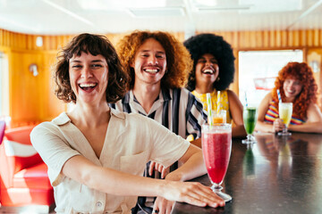 Multiethnic group of friends meeting and drinking milkshakes cocktails at diner restaurant - Multiracial young people bonding and having fun, eating in a fast food burger house
