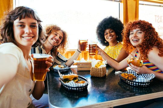 Multiethnic group of friends having meal at 80s vintage diner restaurant - Multiracial young people bonding and having fun, eating in an american fast food burger house - Powered by Adobe