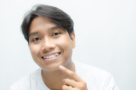 young asian man smiling and showing his crooked teeth isolated over white background. dracula teeth and bucktooth concept. overlapping teeth of man