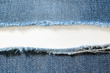 Destroyed torn denim blue jeans fabric frame on white background.