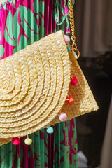 Bolsena, Italy. Straw bag woven with colored cotton balls outside a clothing store in the streets of the town center. Vertical image. 2024-06-21.