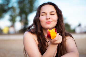 Girl eats juicy peach on the beach. Ripe peach.