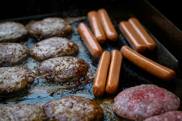Hot Dogs and Hamburgers grilling on a Propane fired Flattop grill. Cooking outside in Summer is an American Family Tradition. Good Food Sizzling.