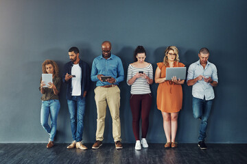 Technology, connectivity and group of business people at wall together with phone, tablet and laptop. Internet, communication and creative team with contact on website, digital network or mobile app