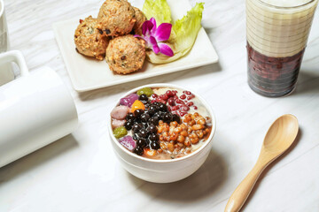 Brown sugar taro balls and grass jelly with dace fish balls, Taiwanese red bean ice tea served in dish isolated on marble background side view of taiwan food